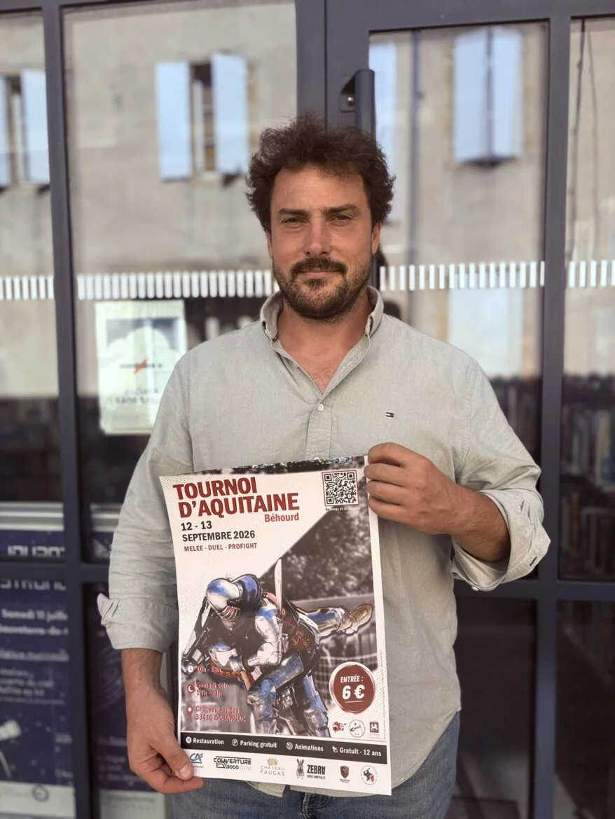 Un homme tient l'affiche du Tournoi d'Aquitaine de béhourd des 12 et 13 septembre 2026 au château Faugas, à Gabarnac.