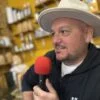 Kevin Rouzier, chapeau clair, micro rouge à la main, au Café Jérémy de Blasimon pendant la première de Entre deux, ça cause