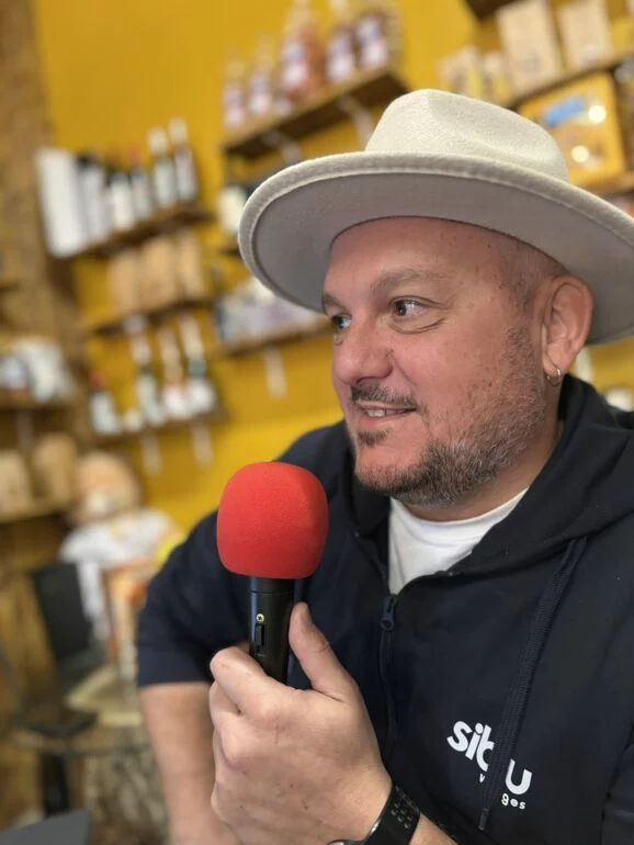Kevin Rouzier, chapeau clair, micro rouge à la main, au Café Jérémy de Blasimon pendant la première de Entre deux, ça cause