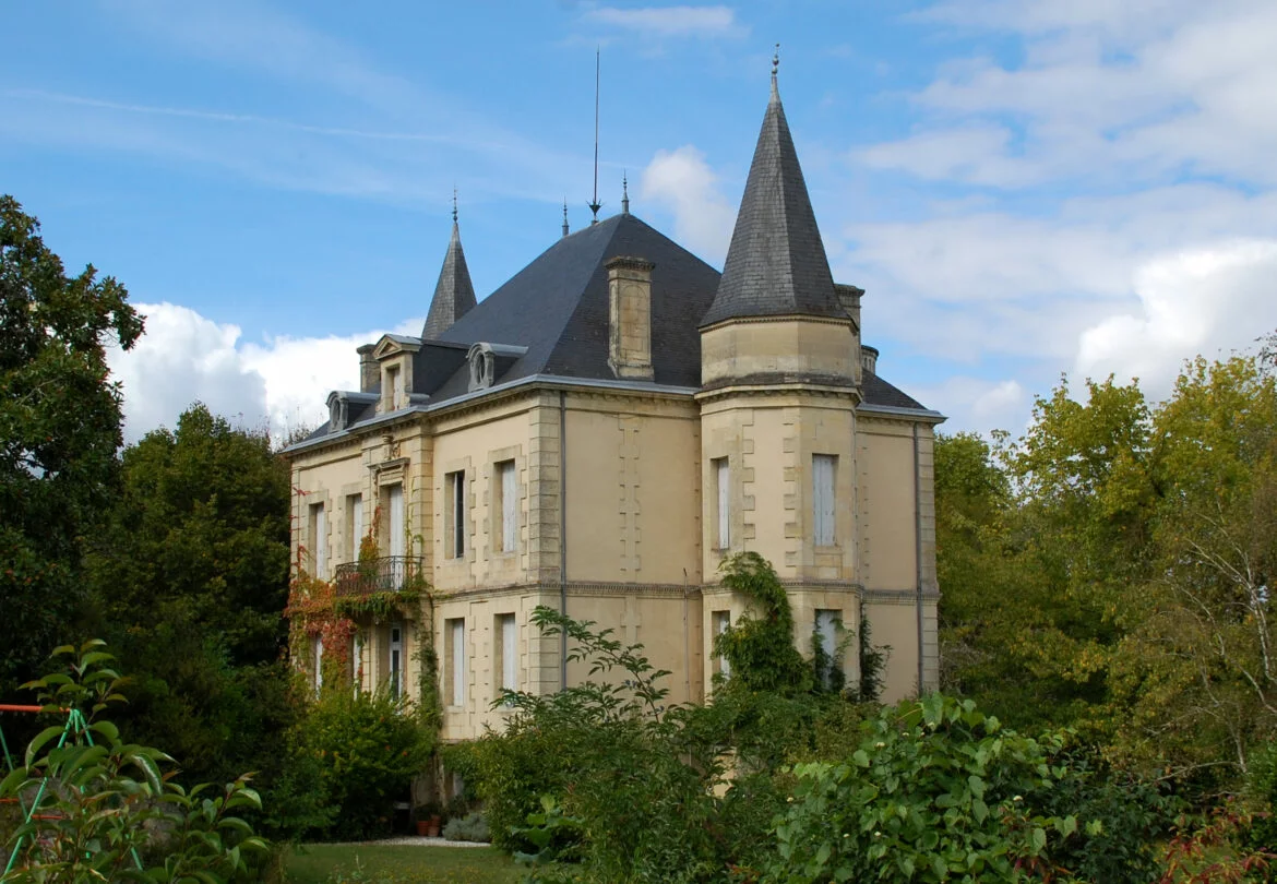 Château de Martignas à Beautiran, en Gironde : façade en pierre claire, toit d'ardoise et tourelle sous un ciel bleu