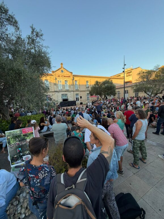 Public rassemblé place des Carmes à Langon pendant le lancement de la saison culturelle, panneau du programme au premier plan.